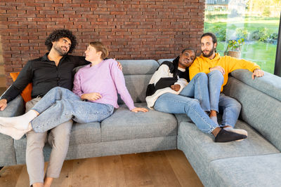 Portrait of smiling friends sitting on sofa at home
