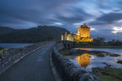 Building by river against cloudy sky