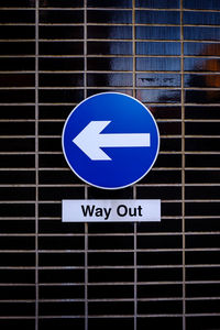 Close-up of text with arrow symbol on metallic railing