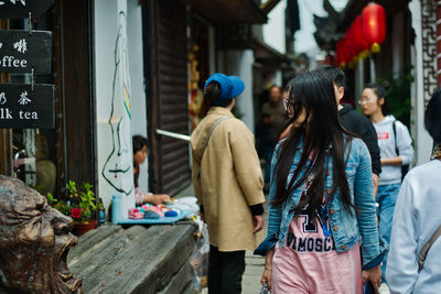 Rear view of people walking on street market in city