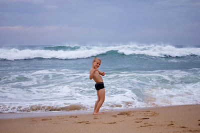 Kid plays on shore of huge, raging ocean. childhood freedom and adventure. discovery of the world