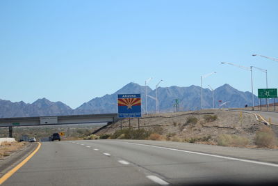 Road sign by mountains against clear blue sky