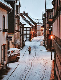 Snow covered road amidst buildings in city