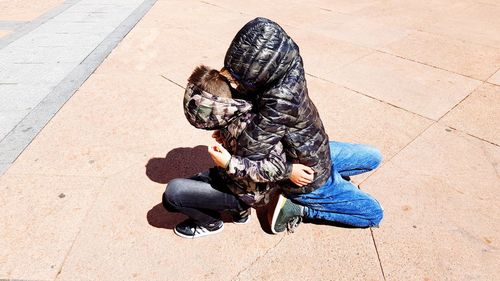 High angle view of woman sitting on footpath