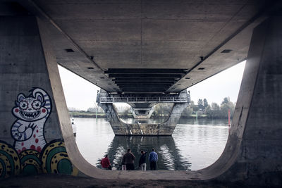 Rear view of people standing under bridge