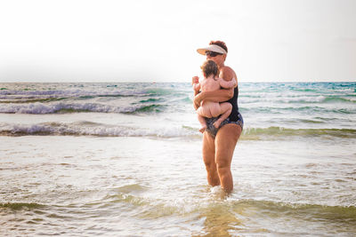 Woman with baby standing in sea