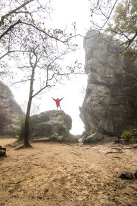 Man standing on rock against sky