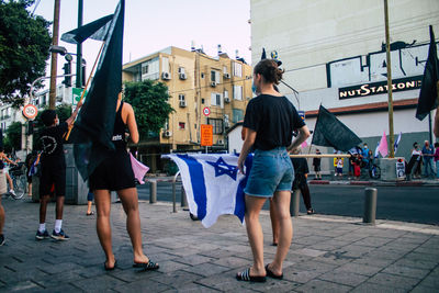 Rear view of women walking on street in city