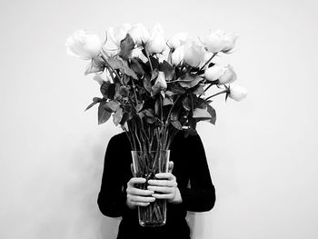 Person holding flower vase against wall