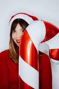 Portrait of smiling young woman holding balloon against white background