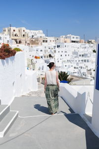 Rear view of woman on steps against buildings at santorini