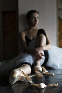 Thoughtful ballet dancer looking away while sitting on floor
