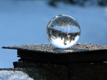 Reflection of crystal ball on glass against clear sky