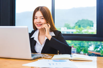 Young woman using mobile phone while sitting on table