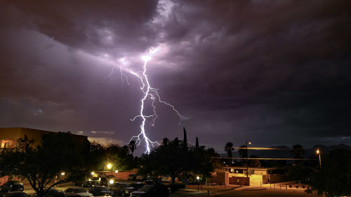 Lightning over illuminated cityscape against dramatic sky