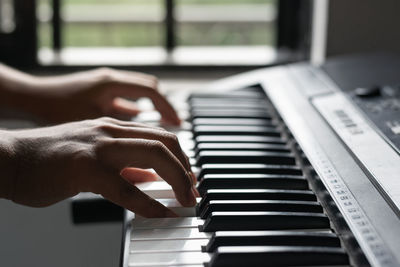 Cropped hand of woman playing piano