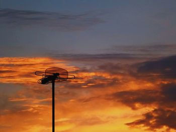 Low angle view of antenna against orange sky