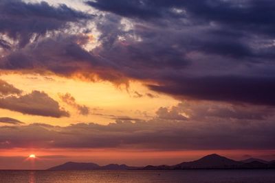 Scenic view of sea against dramatic sky during sunset