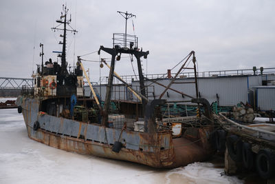 Fishing boat on pier against sky during winter