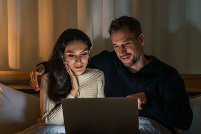 Portrait of man and woman using phone at home