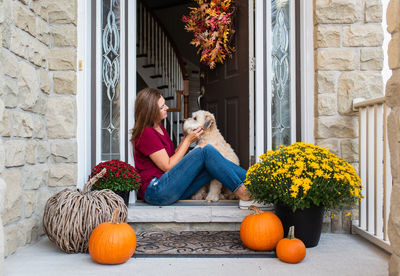 Close-up of woman with dog sitting by door of entrance