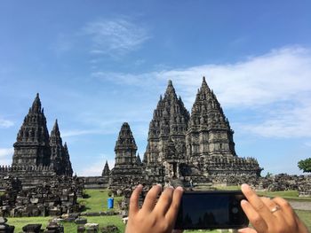 Cropped image of woman photographing building against sky