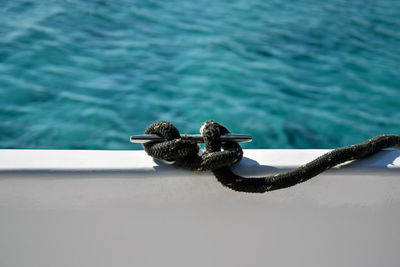 Close-up view nautical rope secured on cleat against blue sea. rope is fixed to side of yacht.