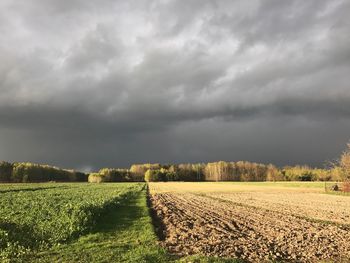 Scenic view of field against storm clouds