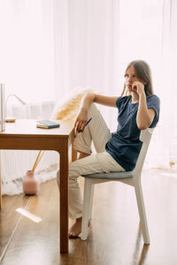 Side view of young woman sitting on sofa at home