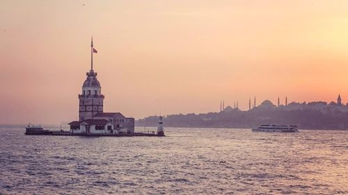 Scenic view of sea against buildings during sunset