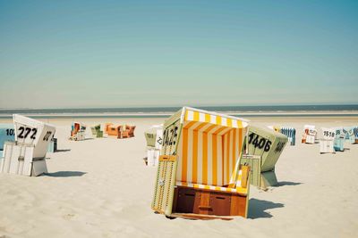 Scenic view of goup of beach baskets on beach against sky