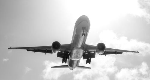 Low angle close-up view of airplane flying against sky