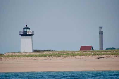 Lighthouse by sea against sky