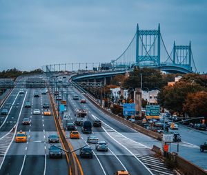 Vehicles on suspension bridge against sky in city