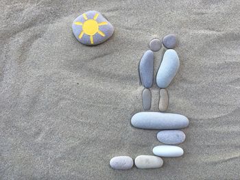 Directly above view of sun drawing on pebble at sandy beach