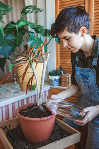 Young girl watering home plants on the balcony, green environment in room, home gardening