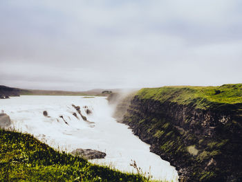 Scenic view of waterfall against sky