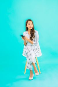 Young woman standing against blue wall