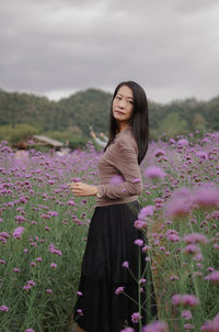 Portrait of young woman standing by flowering plants