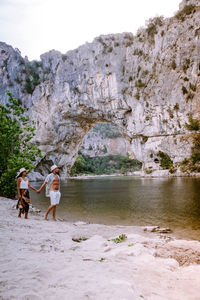 Rear view of people walking on shore against sky