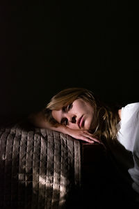 Portrait of young woman standing against black background