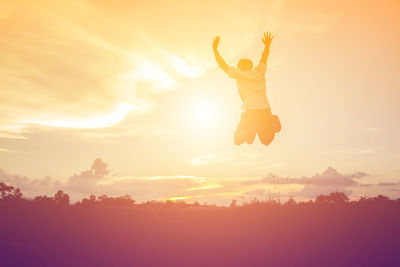 Silhouette man jumping against sky during sunset