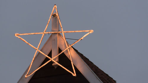 Close-up of illuminated star on top of roof against clear sky