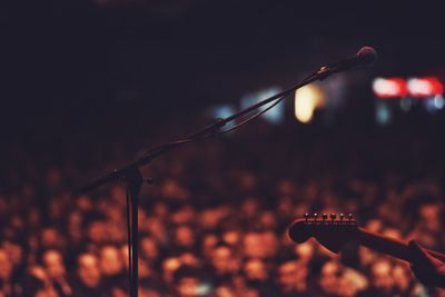 Cropped hand of person playing guitar on stage at concert