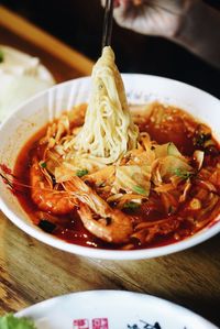 Cropped image of person holding noodles in chopsticks