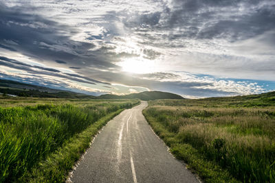 Road amidst field against sky