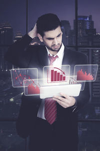 Digital composite image of businessman using digital tablet with graphs