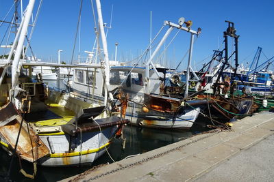 Boats moored at harbor against clear sky