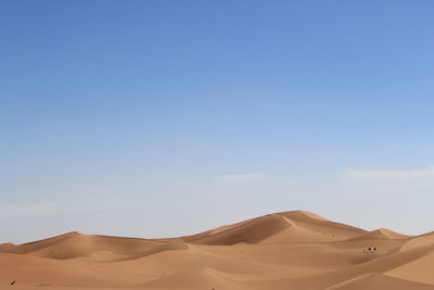 Sand dunes in desert against clear blue sky