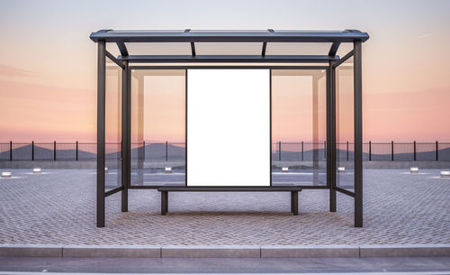 Empty seats by railing against sky during sunset